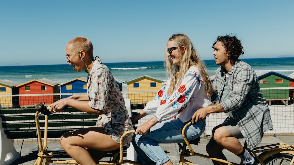 Drei Freunde auf dem Fahrrad am Strand