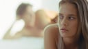 Frau im Bett mit Mann im Hintergrund