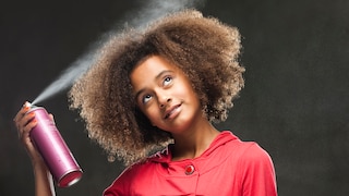 Frau, die sich die Haare einsprüht