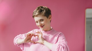 Frau macht Herzsymbol mit ihrer Hand