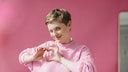 Frau macht Herzsymbol mit ihrer Hand