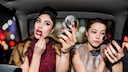 Zwei Frauen schminken sich im Auto