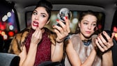 Zwei Frauen schminken sich im Auto