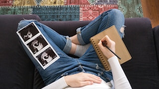 Schwangere Frau auf dem Sofa mit Umstandshose