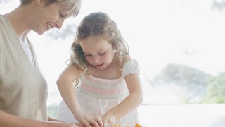 Frau und Kind pressen Saft aus Orangen