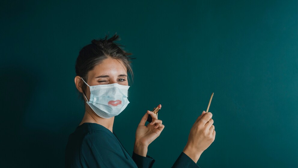 Frau mit Mundschutz und Kostmetik in der Hand