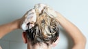 Frau schäumt sich die Haare ein