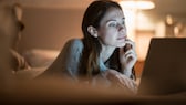 Frau am Laptop mit Blaulicht auf der Haut