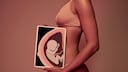 Frau hält vorm Bauch ein Tablet, das eine Röntgenaufnahme eines Babys zeigt