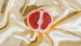 Aufgeschnittene Grapefruit in Nahaufnahme auf einem Seiden-Tuch