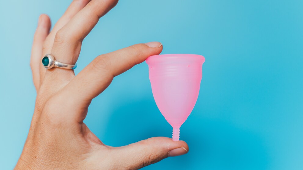 Frau hält eine pinke Menstruationstasse