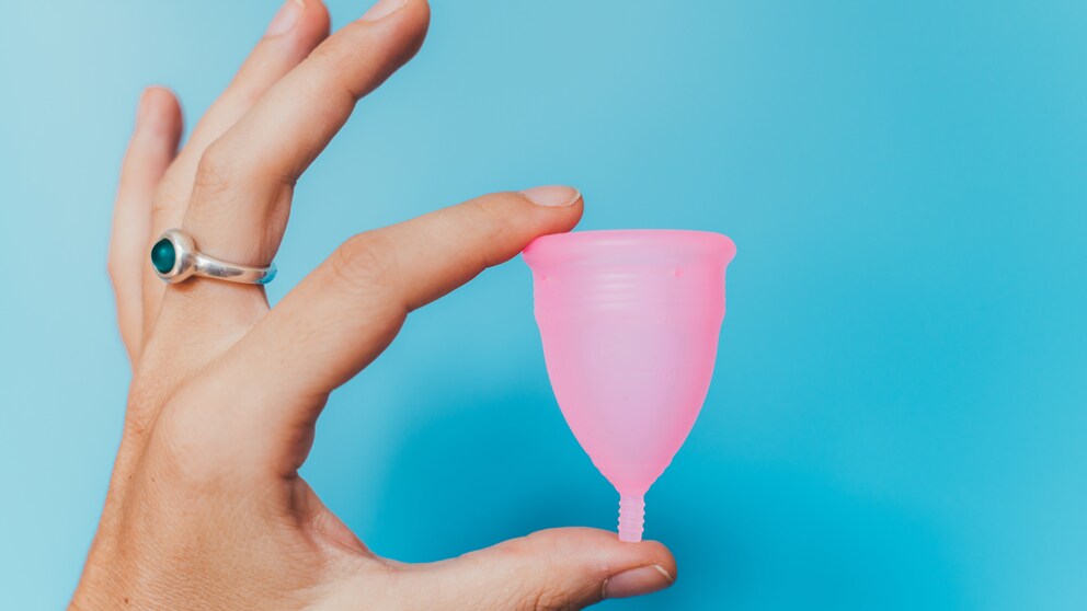 Frau hält eine pinke Menstruationstasse