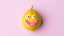 Happy lemon fruit with face on pink background