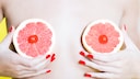 Frau, die sich Grapefruit-Scheiben von ihre Brüste hält