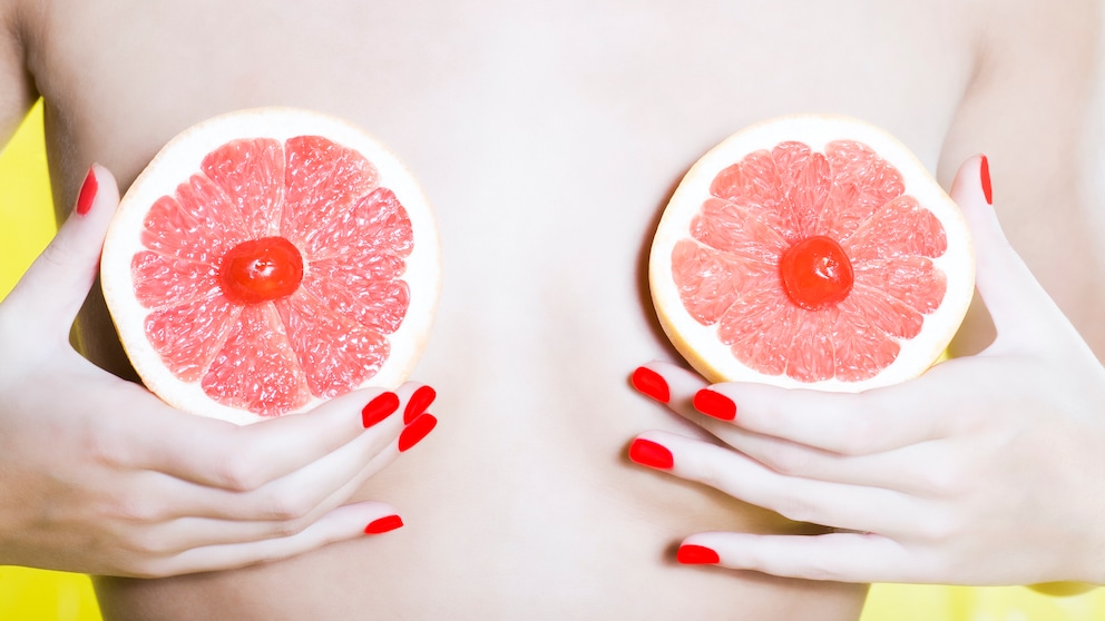 Frau, die sich Grapefruit-Scheiben von ihre Brüste hält