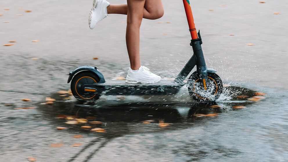 Frau fährt durch Regen auf einem Scooter