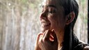 Frau steht unter der Dusche. Dank einer kürzeren Duschdauer und kühleren Temperatur können Sie Strom sparen.