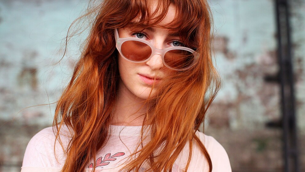 Frau mit roten Haaren trägt Sonnenbrille