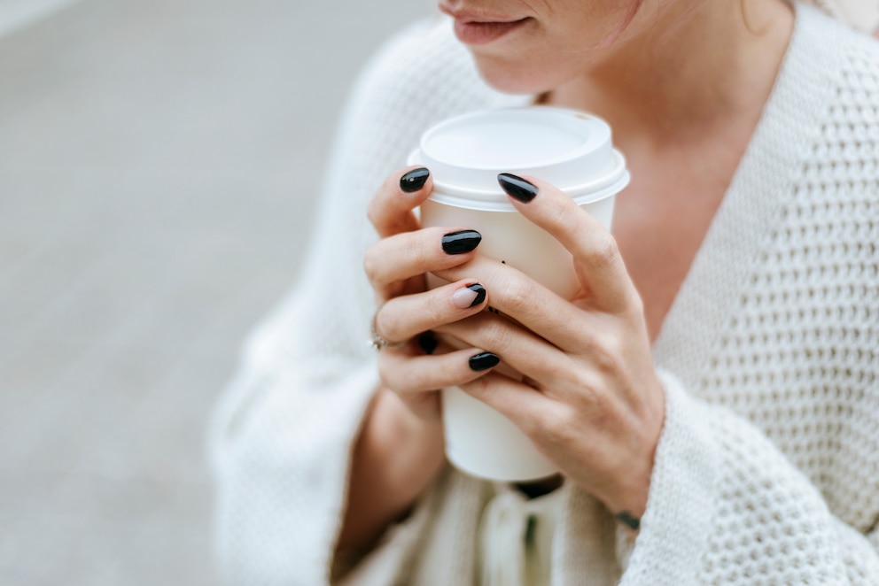 Frau mit braunem Nagellack und Kaffee