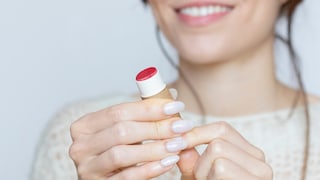 Frau mit Lippenpflege in der Hand