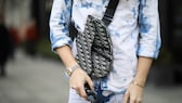 Bild mit Close up von Tasche, Hemd, Sonnenbrille und Händen