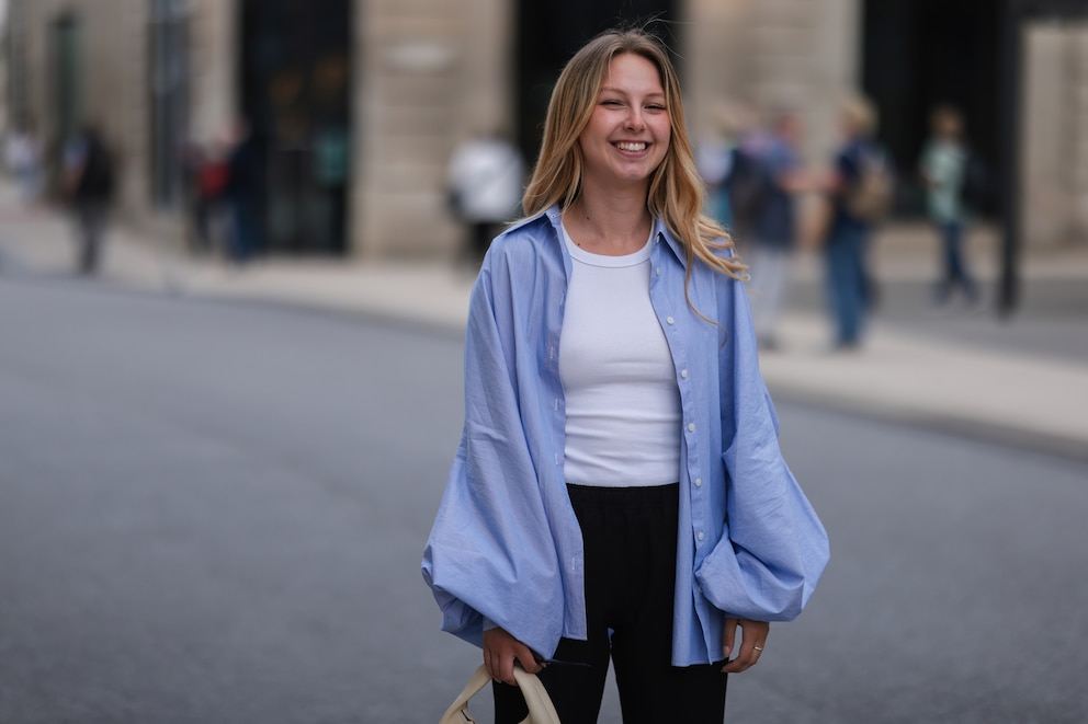 Lächelnde Frau mit blauer Bluse, weißem Shirt und schwarzer Hose