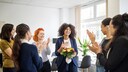 Frauen im Büro klatschen für eine Kollegin oder Chefin