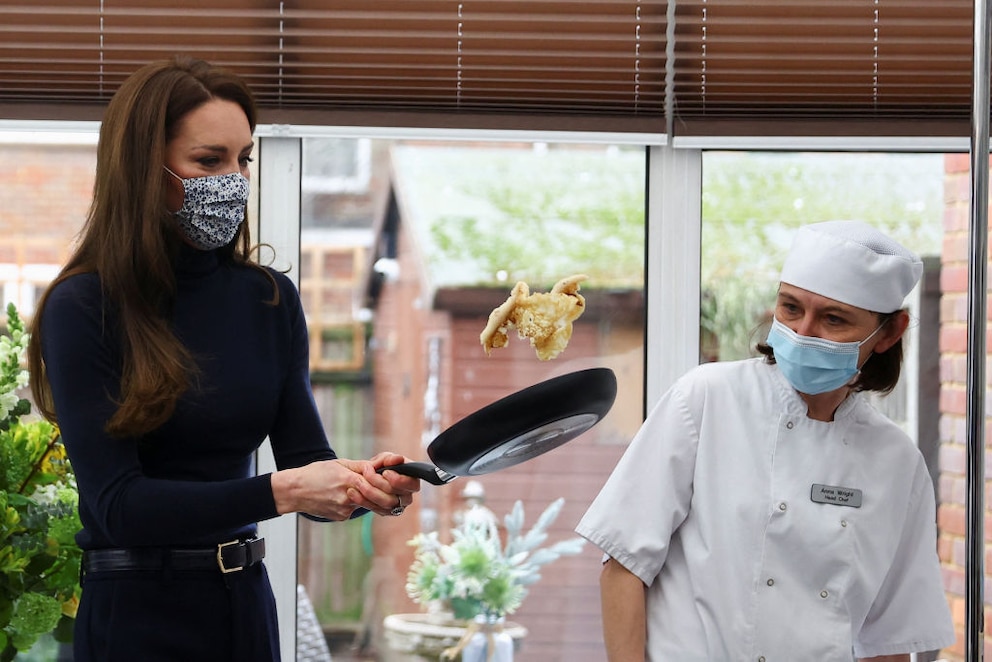 Prinzessin Kate wendet einen Pfannkuchen – oder eher Teile davon – mit der Pfanne in der Luft und sieht sehr konzentriert aus