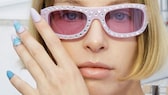 Model auf Mailänder Fashion Week mit rosa Sonnenbrille und bezaubernd rosa-hellblauen Nägeln.