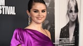 Selena Gomez auf dem roten Teppich in einem One-Shoulder-Satin-Kleid in Pink-Lila mit Smokey Eyes, langen funkelnden Ohrringen und einem sehr süßen Lächeln.