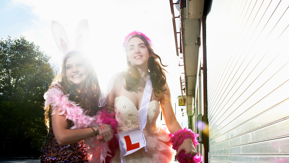 Zwei junge Frauen in Kostümen auf dem Weg zum JGA. Sie lachen, aber ob sie wirklich Spaß haben? Es ist ein Fotoshooting, also wahrscheinlich ja. Aber es werden immer weniger, die Lust auf diesen „klassischen“ JGA haben, oder?