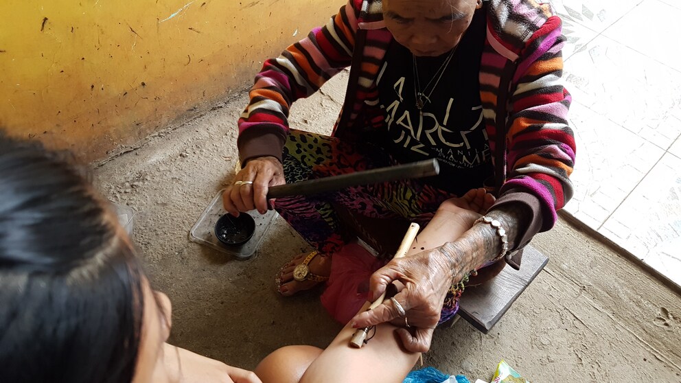 Apo Whang-Od geht ihrer Arbeit als Tätowiererin der traditionellen Batok nach. Früher Kopfjägern als Auszeichnung oder Frauen als Schönheitsmerkmal verliehen, tätowiert die 106-Jährige heute unzählige Touristen.