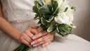 Braut mit French Manicure mit weißen Ornamenten, im Brautkleid und einem Blumenstrauß in der Hand