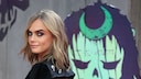 Cara Delevigne lächelt über ihre Schulter in die Kamera. Ihr Make-up ist intensiv und sehr schön, ihre Augenbrauen kommen gut zur Geltung.