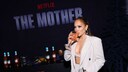 JLo mit einem Drink auf der Premiere ihres Films The Mother in LA. Sie trägt einen sandfarbenen, weit geschnittenen Hosenanzug mit einem Bralette, zurückgebundenes Haar und starkes Augen-Make-up. Ihre Hände halten eine Baguette-Clutch und lassen so einen guten Blick auf die Clean Nails-Nägel zu