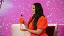 Ashley Graham im orangefarbenen Kleid mit ihrer Barbie-Puppe im selben Kleid
