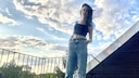 Carmen in Paggy-Jeans, Crop-Top und Pumps auf ihrem Balkon mit Opas selbstgezogener Palme