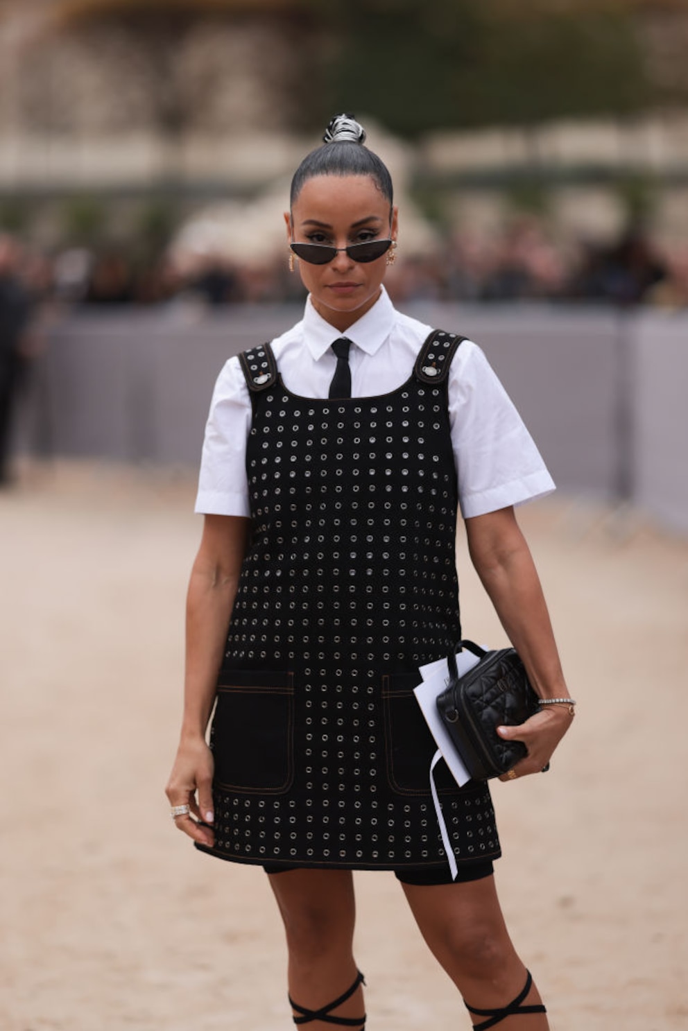 Junge Frau mit Sleek Bun im schwarzen Nietenkleid mit weißer Bluse darunter in Paris