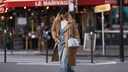Junge Frau in Paris auf der Straße mit all-over-Jeans im weiten Schnitt und beigem Trench