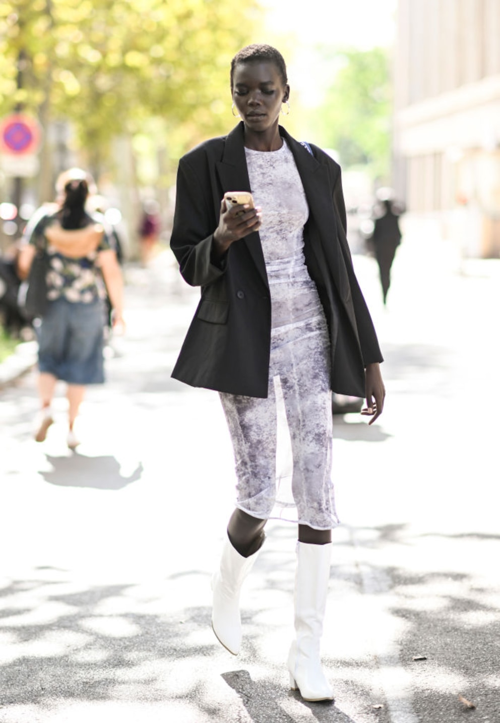 Junges Model im weißen transparenten Kleid mit weißen Stiefeln und schwarzem Blazer in Paris. Hach, da muss man doch davon ausgehen, dass alle in Paris gut gekleidet sind oder?