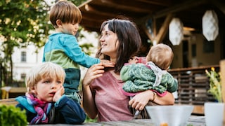 Frau mit drei Kindern im Garten