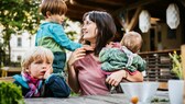 Frau mit drei Kindern im Garten