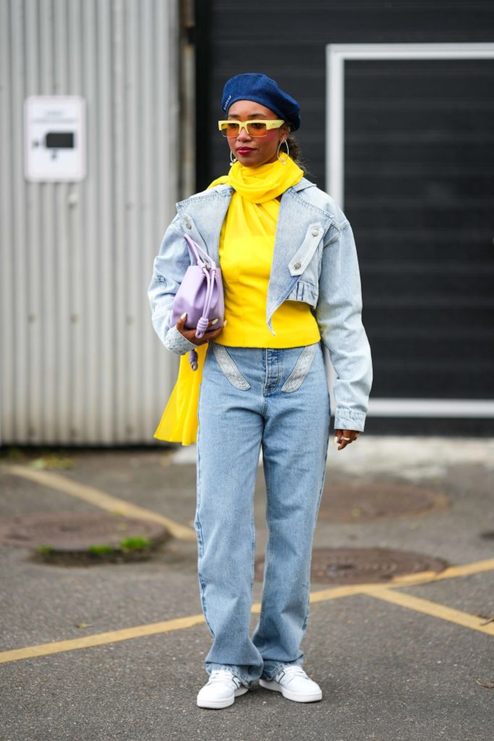 Frau im gelben Pulli mit passender Brille, Schal und Blue Jeans und Jeansjacke