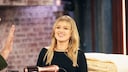 Die umwerfende Kelly Clarkson mit einem fransigen Pony, wie sie knapp an der Kamera vorbeigrinst.