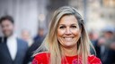 Königin Máxima der Niederlande im roten Outfit, wie sie freudig in die Kamera grinst und dabei sehr symapthisch aussieht