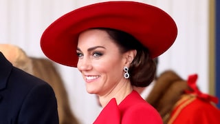 Prinzessin Kate mit großem Hut und Cape mit Schleife in Knallrot