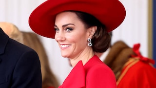 Prinzessin Kate mit großem Hut und Cape mit Schleife in Knallrot