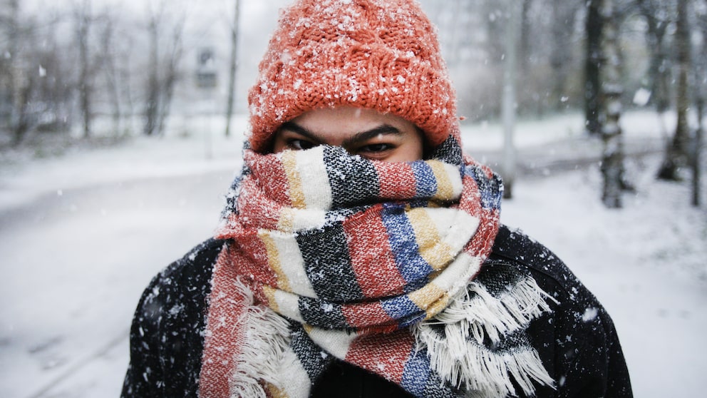 Junge Frau mit Mütze und Schal im Schnee