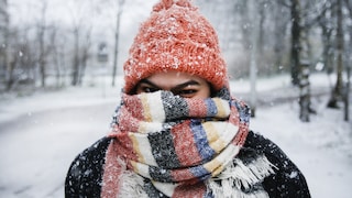 Junge Frau mit Mütze und Schal im Schnee