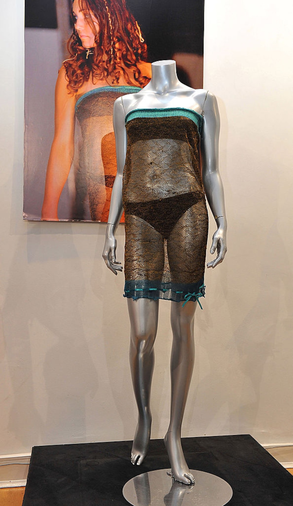 Transparentes Kleid in Ausstellung. Dahinter ein Foto von Kate Middleton darin bei einer Fashionshow 2002
